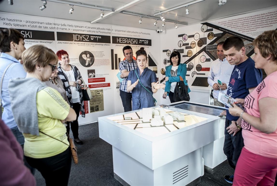 Grupa osób stoi wokół makiety prezentowanej na wystawie "Muzeum na kółkach"