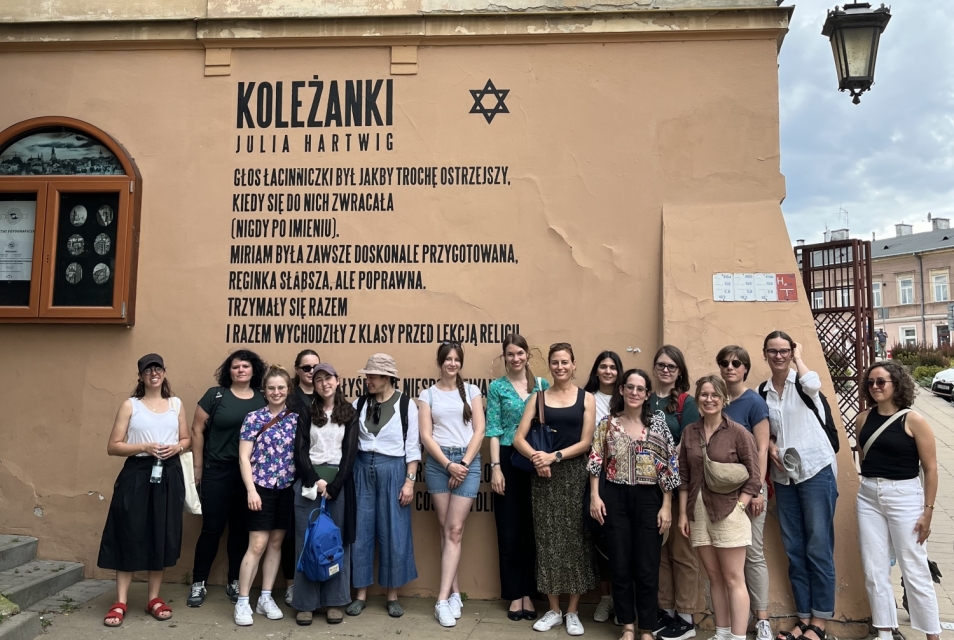Uczestnicy i uczestniczki Szkoły letniej stoją przy muralu z wierszem Julii Hartwig w Lublinie.
