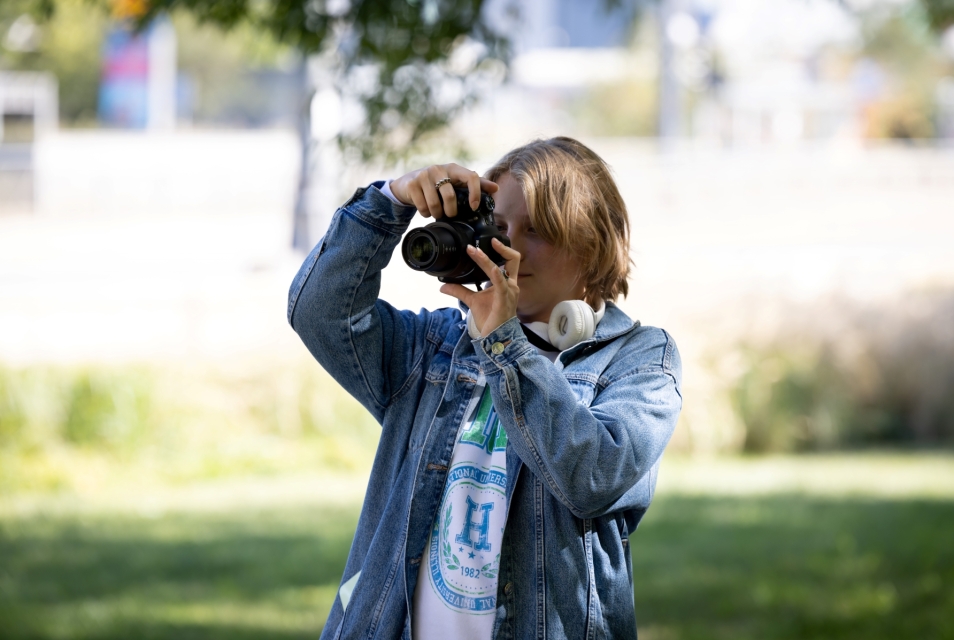 Chłopak robi w parku zdjęcie aparatem fotograficznym.