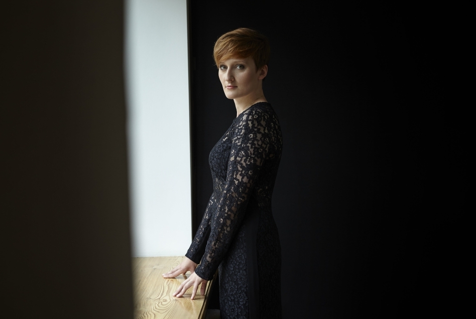 In a dark room, a woman – Marta Kluczyńska – can be seen in a narrow strip of light.