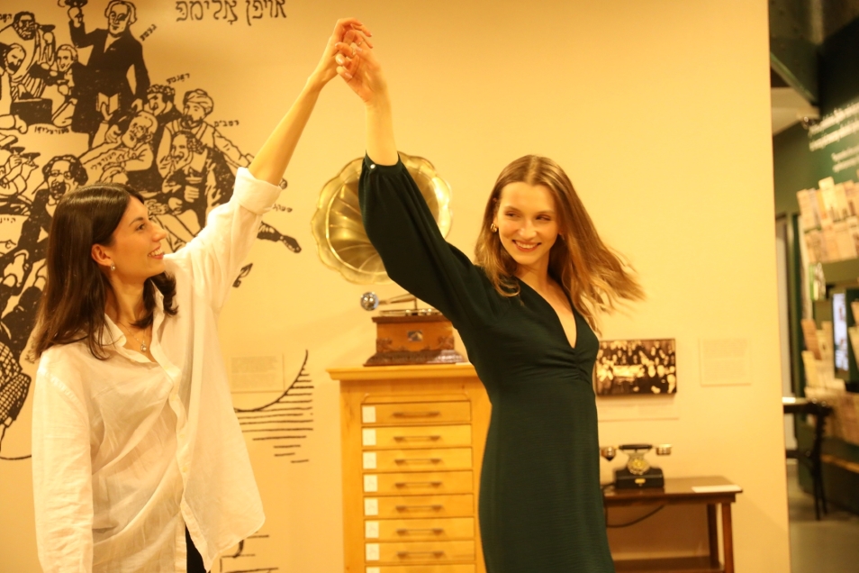 A brunette and a blonde are dancing together in the permanent exhibition in the room with the gramophone.