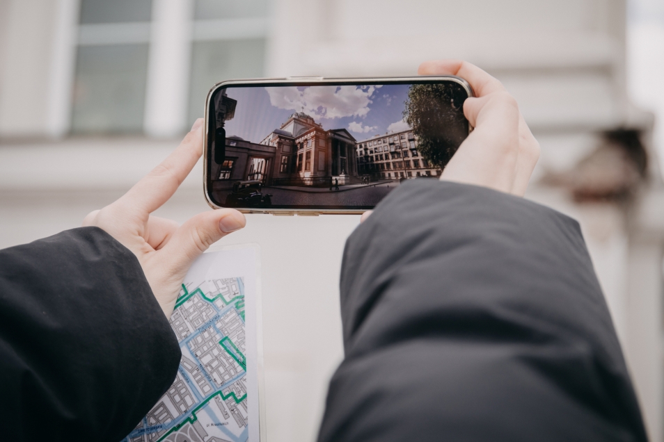 Ktoś trzyma przed telefon. Na ekranie wyświetla się zdjęcie dawnej synagogi na Tłomackiem.