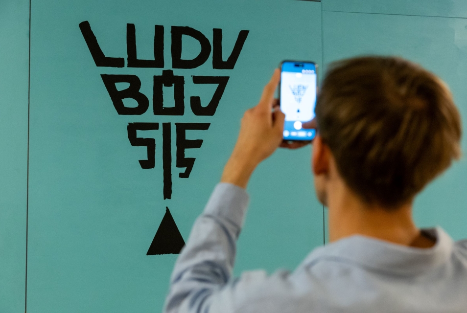 Jedna osoba robi zdjęcie logotypowi wystawy "Ludu, bój się"