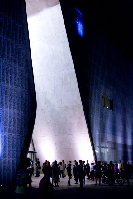 Wieczór, kolejka osób przed oświetlonym wejściem do Muzeum Polin. Oczekują na zwiedzanie w ramach "Nocy Muzeów".