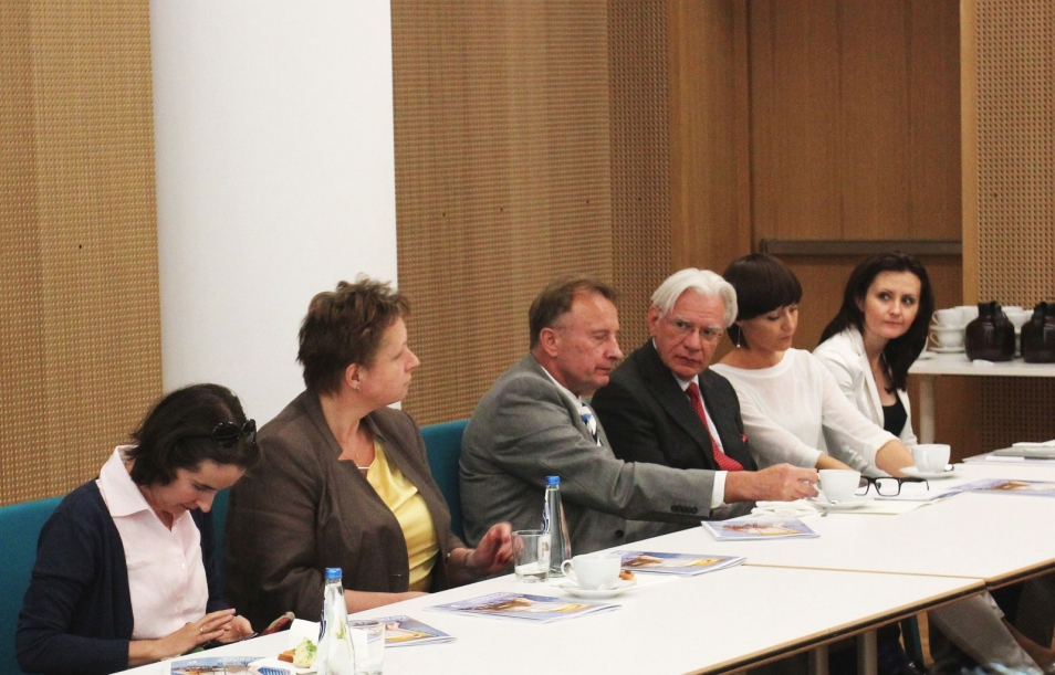 Kilku panelistów siedzi przy stole.