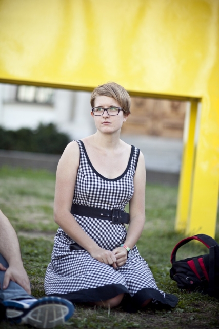 Dziewczyna klęczy na trawie.