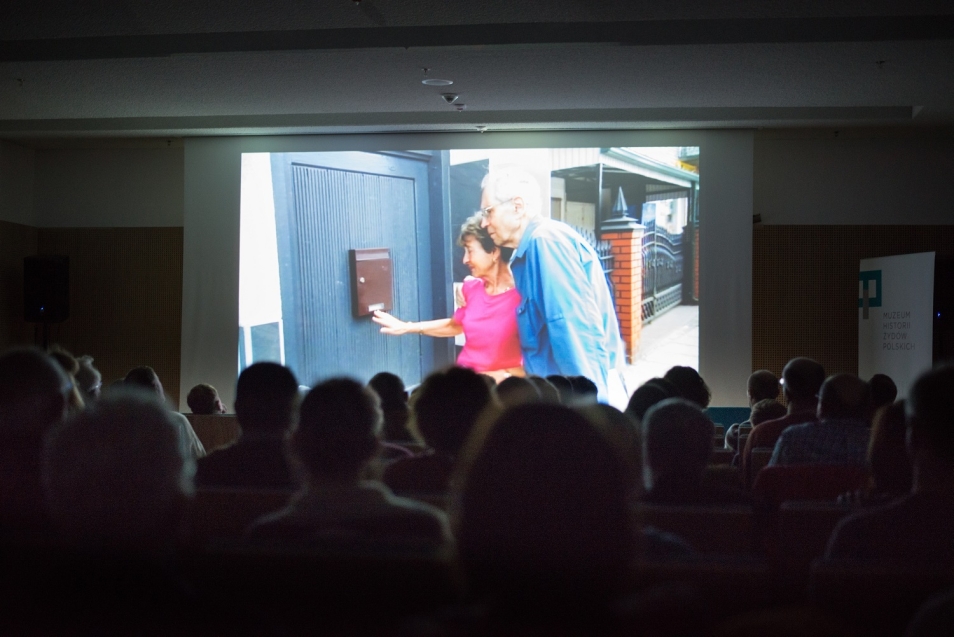 Grupa ludzi ogląda na ekranie film lub zdjęcia.