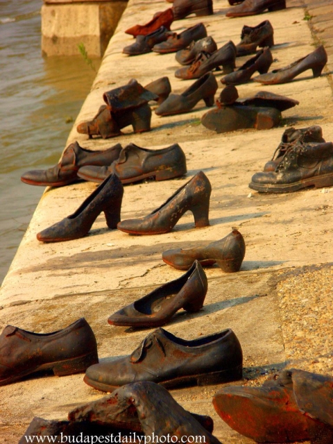 Różne buty stoją na posadzce - prawdopodobnie jest to fragment jakiejś instalacji.