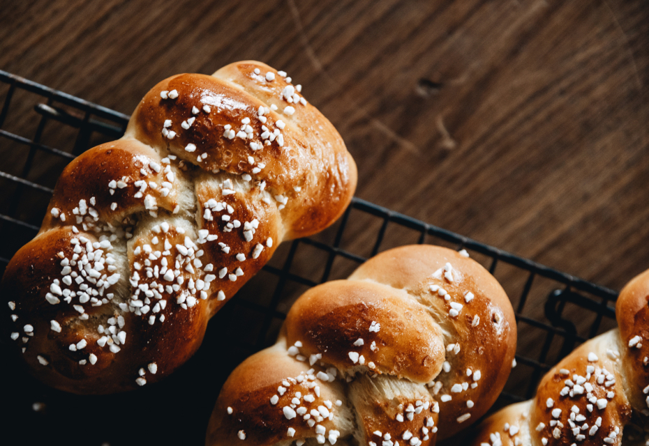 Kolacja szabatowa z Leah Koenig w ramach TISZ Festiwalu w Muzeum POLIN. Na zdjęciu: na kratce do pieczenia leżą obok siebie trzy pięknie wypieczone chałki, posypane grubym cukrem.