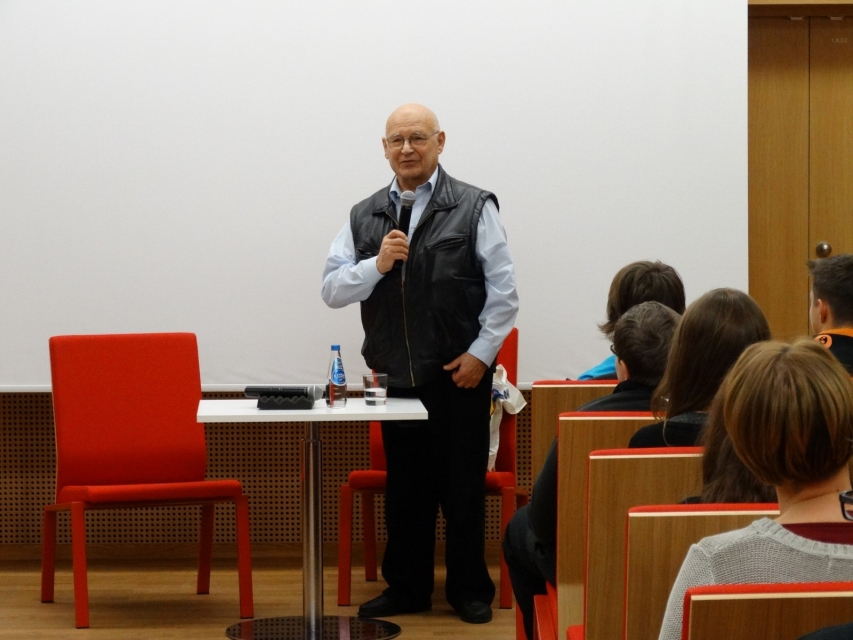 Starszy mężczyzna mówi przez mikrofon podczas spotkania.