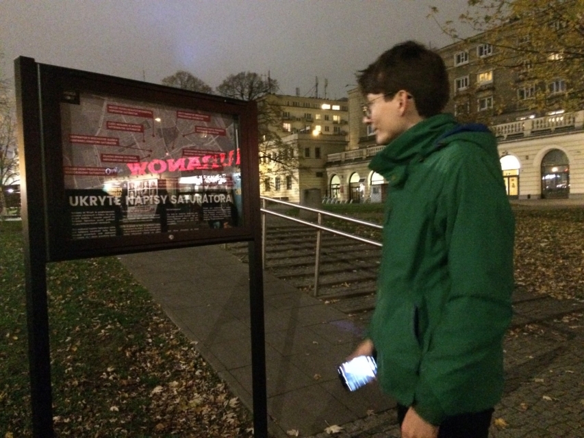 Kobieta ogląda pracę z Galerii Muranów w przestrzeni miejskiej.