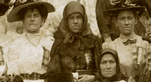 Czarno-białe zdjęcie przedstawia grupę kobiet w chustach i kapeluszach.