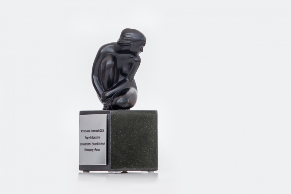 Statuetka przedstawiająca siedzącego, zwróconego do boku mężczyznę.