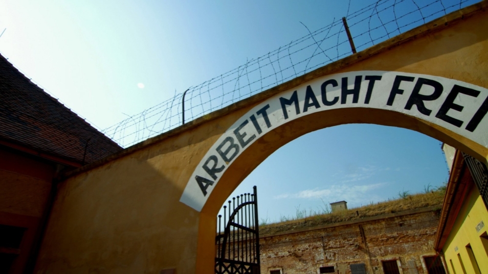 Widok na bramę w obozie Auschwitz z napisem Arbeit macht frei.