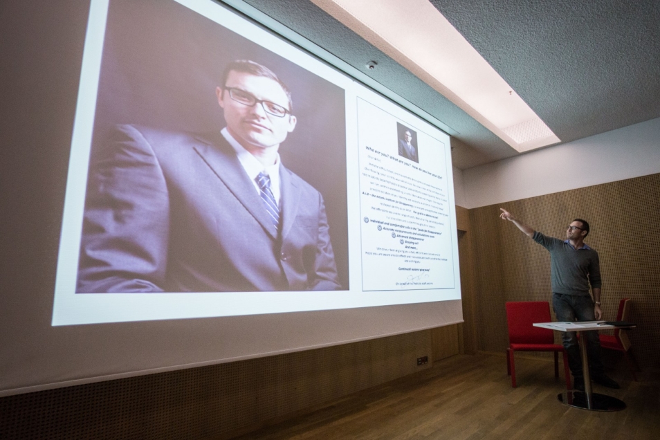 Sala wykładowa. Prowadzący pokazuje ręką na wyświetlane zdjęcie mężczyzny