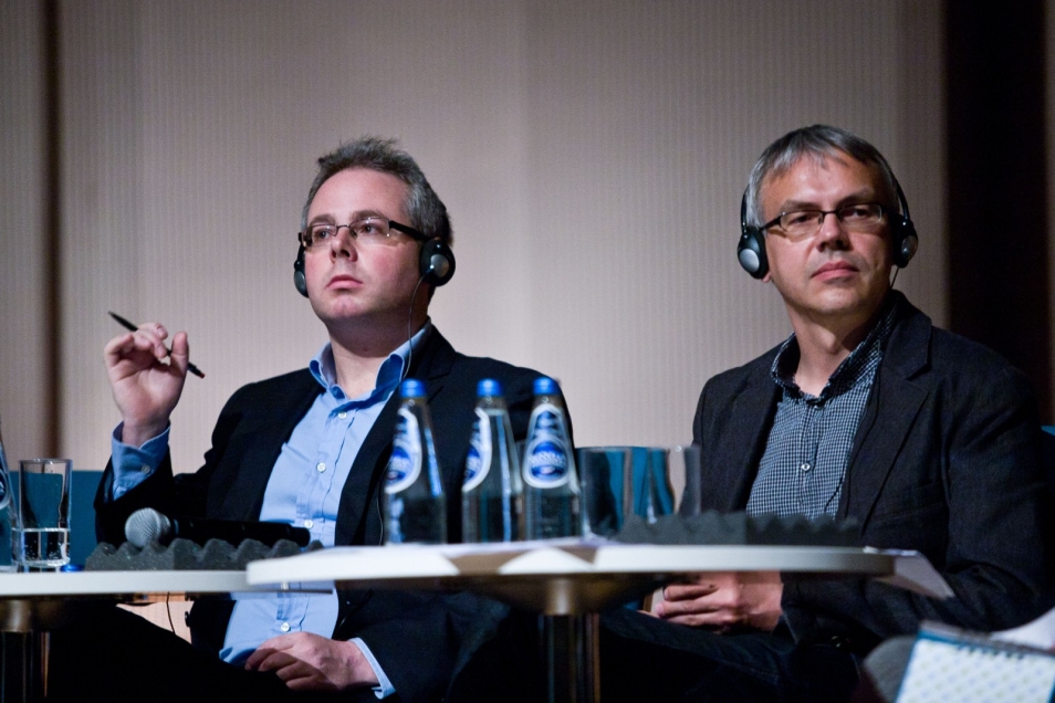 Dwaj mężczyźni siedzą przy stole podczas debaty.