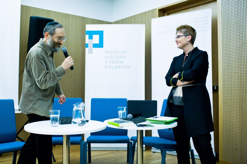 Spotkanie w Muzeum POLIN. Żyd w mycce stoi z mikrofonem zwrócony w stronę kobiety.