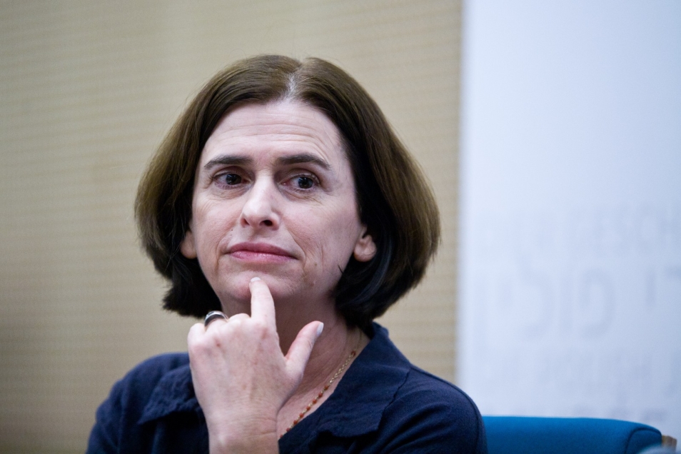 Zamyślona brunetka trzyma palec na brodzie.