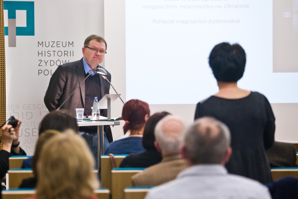 Mężczyzna przemawia przy pulpicie z mikrofonem.