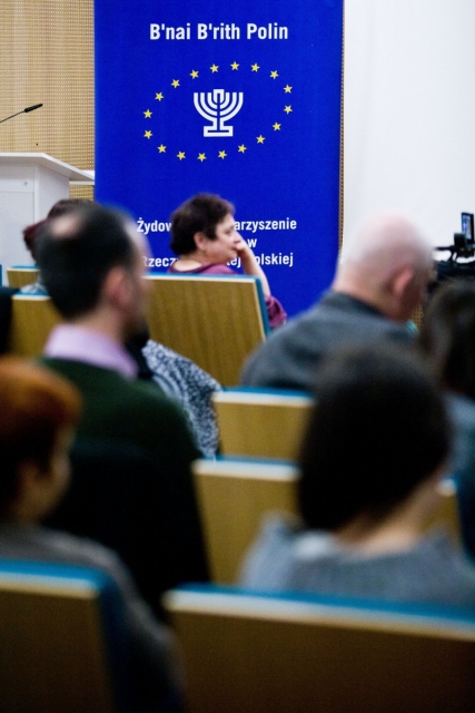 Grupa uczestników debaty o marcu '68 siedzi w sali.