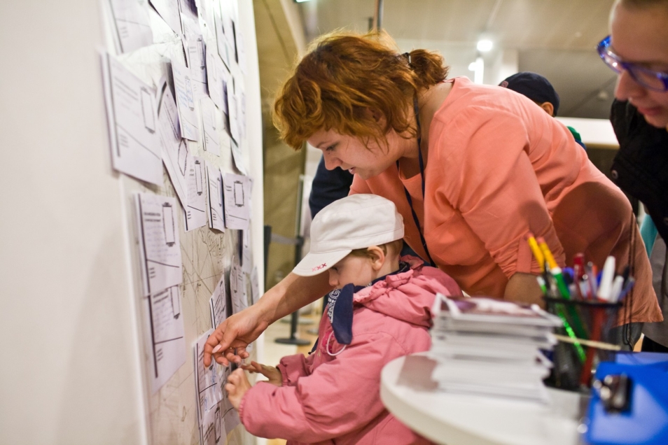 Mama i córka przyklejają karteczki na ścianę podczas Nocy Muzeów.