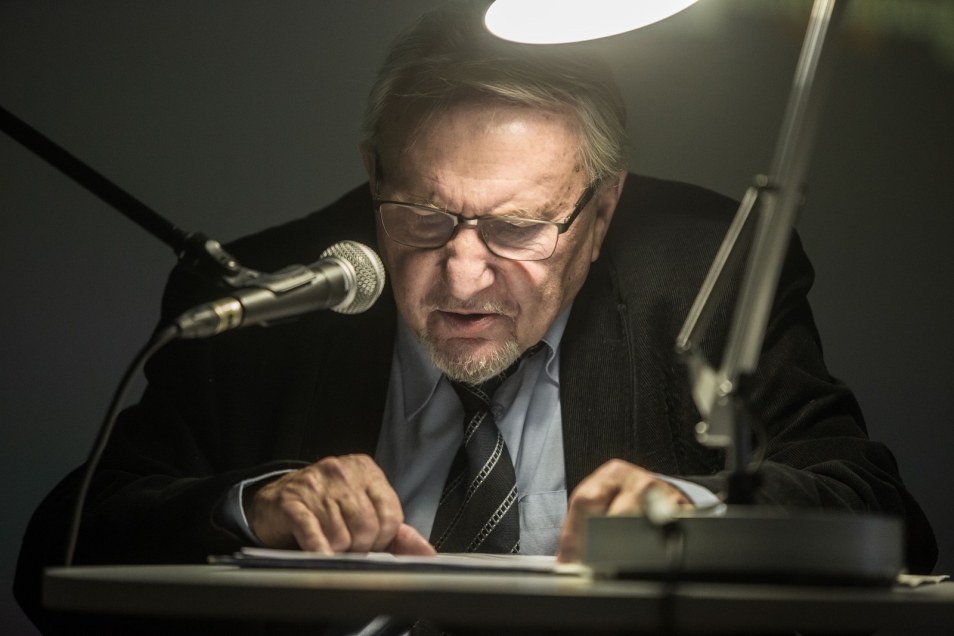 HACKING. Mężczyzna pochyla się nad mikrofonem i czyta.