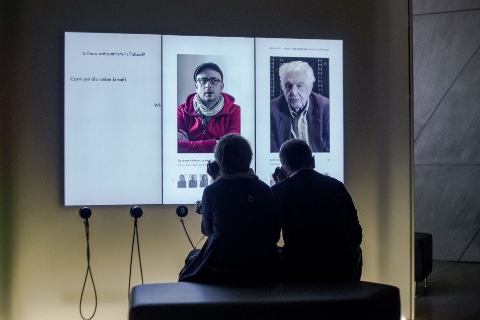 HACKING. Dwie osoby siedzą przed ekranem multimedialnym i oglądają zdjęcia.