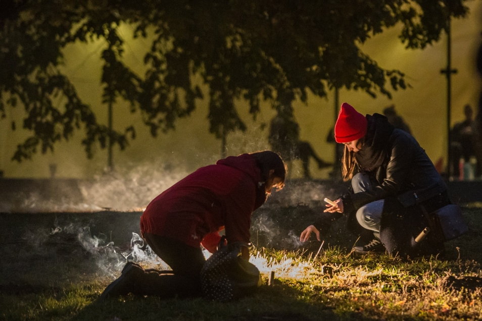 Półmrok. Dwie osoby klęczą na trawie. Próbują rozpalić ognisko.