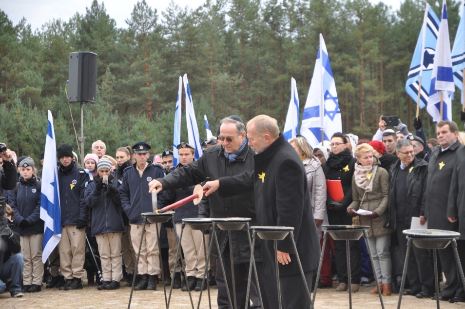 Dwaj mężczyźni zapalają pochodnie - w tle flagi izraelskie.