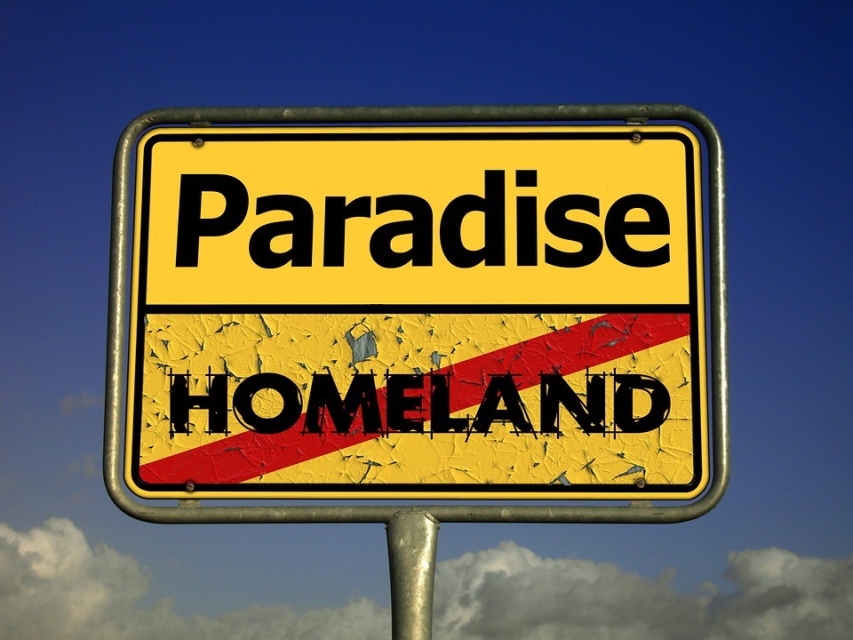 Żółty znak drogowy. Na nim dwa napisy Paradise i przekreślony czerwoną linią napis Homeland.