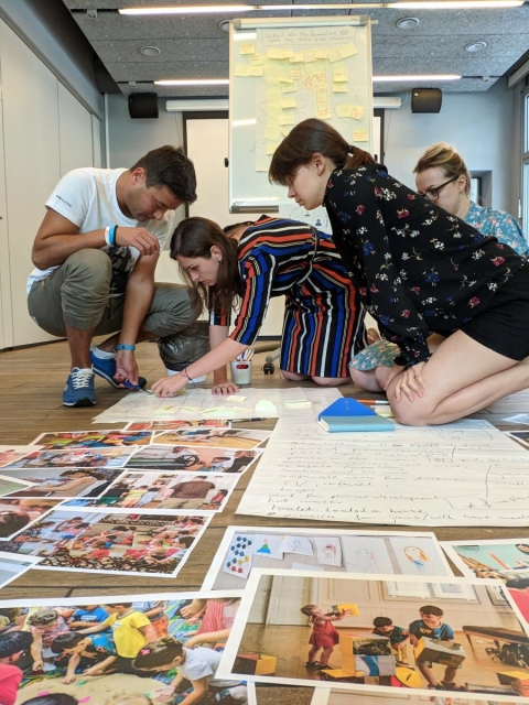Podsumowanie projektu "EDU-NET: EAST. Przez edukację nieformalną do nowych liderów”. Na zdjęciu: uczestnicy programu podczas warsztatów, w sali edukacyjnej. Klęczą nad rozłożonymi na podłodze planszami roboczymi
