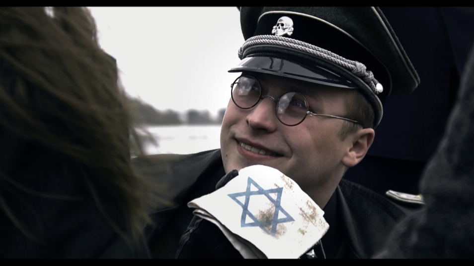 Scena z filmu pt. "Szukając gwiazd". Na pierwszym planie niemiecki żołnierz trzyma opaskę z gwiazdą Dawida.