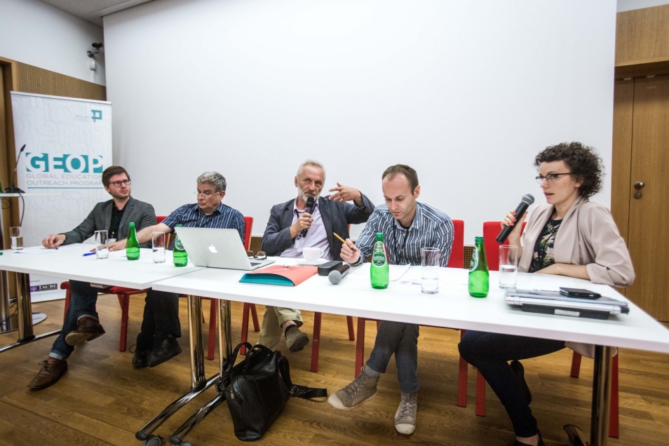 A group of speakers sit at a table during a workshop.