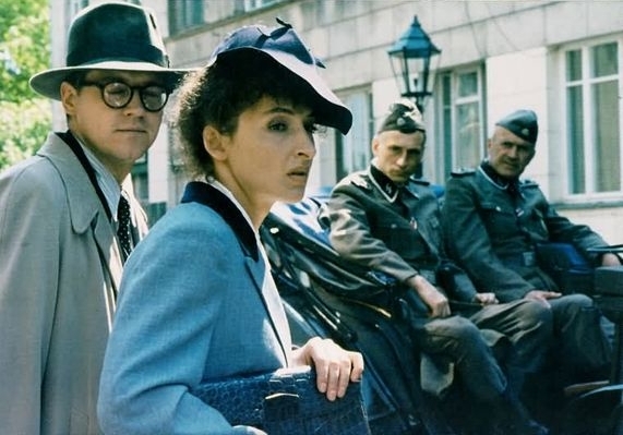 Kadr z filmu "Wielki tydzień". Kobieta i mężczyzna w kapeluszach. Za nimi dwaj żołnierze.