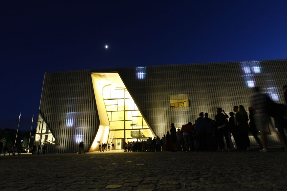 Kolejka ludzi stoi nocą przed muzeum POLIN w Noc Muzeów.