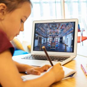 Na obrazie widzimy dziecko siedzące przy monitorze komputera w czasie zajęć edukacyjnych.  