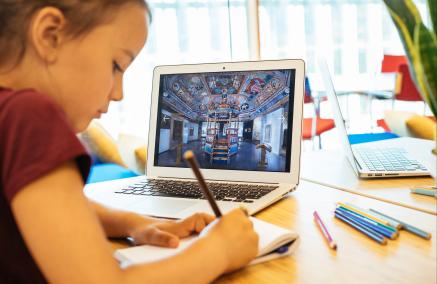 Na obrazie widzimy dziecko siedzące przy monitorze komputera w czasie zajęć edukacyjnych.  