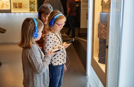 Dzieci z audioprzewodnikami zwiedzają wystawę muzeum 