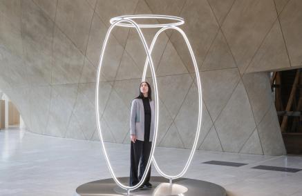 Dziewczyna stoi w środku instalacji świetlnej "Echo" prezentowanej w holu głównym Muzeum POLIN.