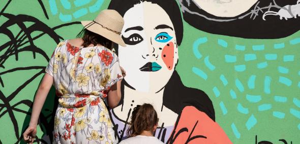 Mural na Łące Leśmiana. Dwie osoby malują szczegóły kobiecej twarzy.