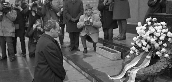 Zdjęcie archiwalne biało-czarne z 1970 roku, na którym kanclerz RFN Willy Brandt wykonuje symboliczny gest - klęka przed pomnikiem Bohaterów Getta w Warszawie, oddając hołd ofiarom Zagłady.