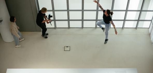 Widok z góry - po lewej mężczyzna, który trzyma kamerę, po prawej tancerka baletowa - tańczy