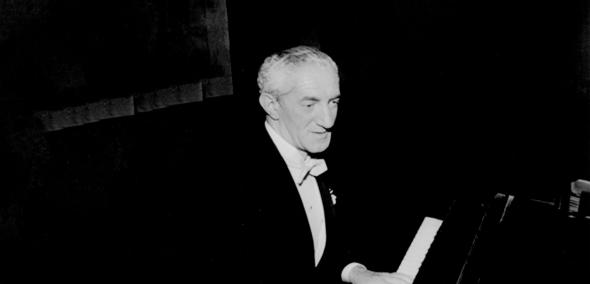 Czarno-białe zdjęcie przedstawia Henryka Warsa przy fortepianie. Ubrany jest w czarny frak i białą koszulę.