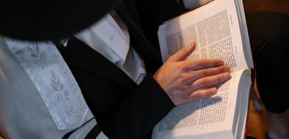 Mężczyzna w tradycyjnym stroju żydowskim czyta Torę