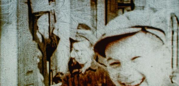 Kadr z filmu "Trzy minuty zawieszone w czasie". Młody chłopak uśmiecha się, za nim stoi mężczyzna.