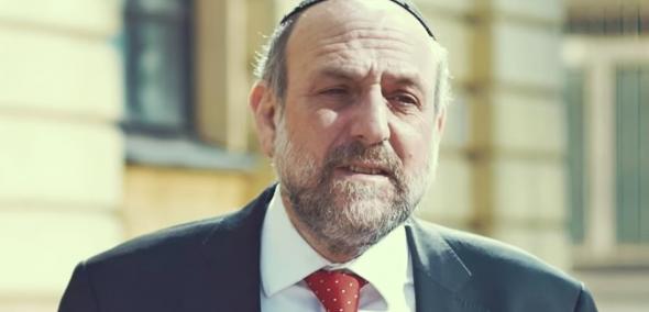 Rabin Michael Schudrich z papierowym żonkilem przypiętym do garnituru.