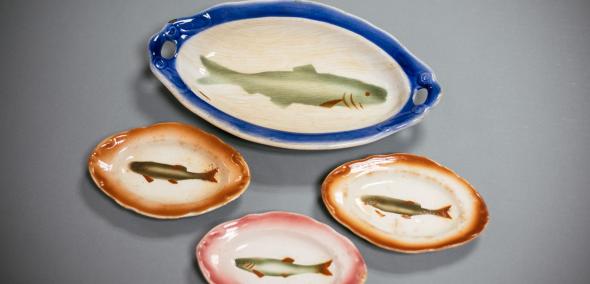 Zestaw czterech półmisków, na których namalowane są ryby. Jeden talerz większy, trzy mniejsze. Każdy z nich ma kolorowe obwódki.
