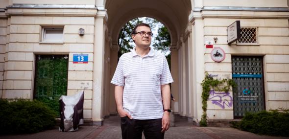 Mariusz Jastrząb stoi przy kamienicy na warszawskim Muranowie.