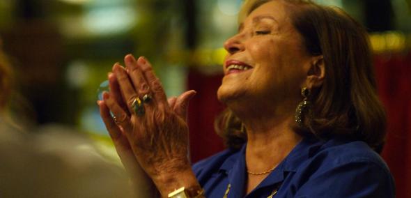 Kadr z filmu "Rose". Starsza kobieta ma przymknięte oczy, a dłonie złożone jak do modlitwy.