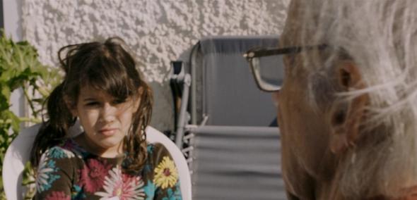 Kadr z filmu "Odrzuceni w Ziemi Obiecanej". Naprzeciwko siebie siedzą starszy mężczyzna i młoda kobieta. 